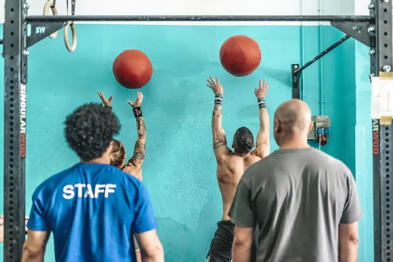 Clase de WOD lanzando balones medicinales contra la pared, con un entrenador del staff
